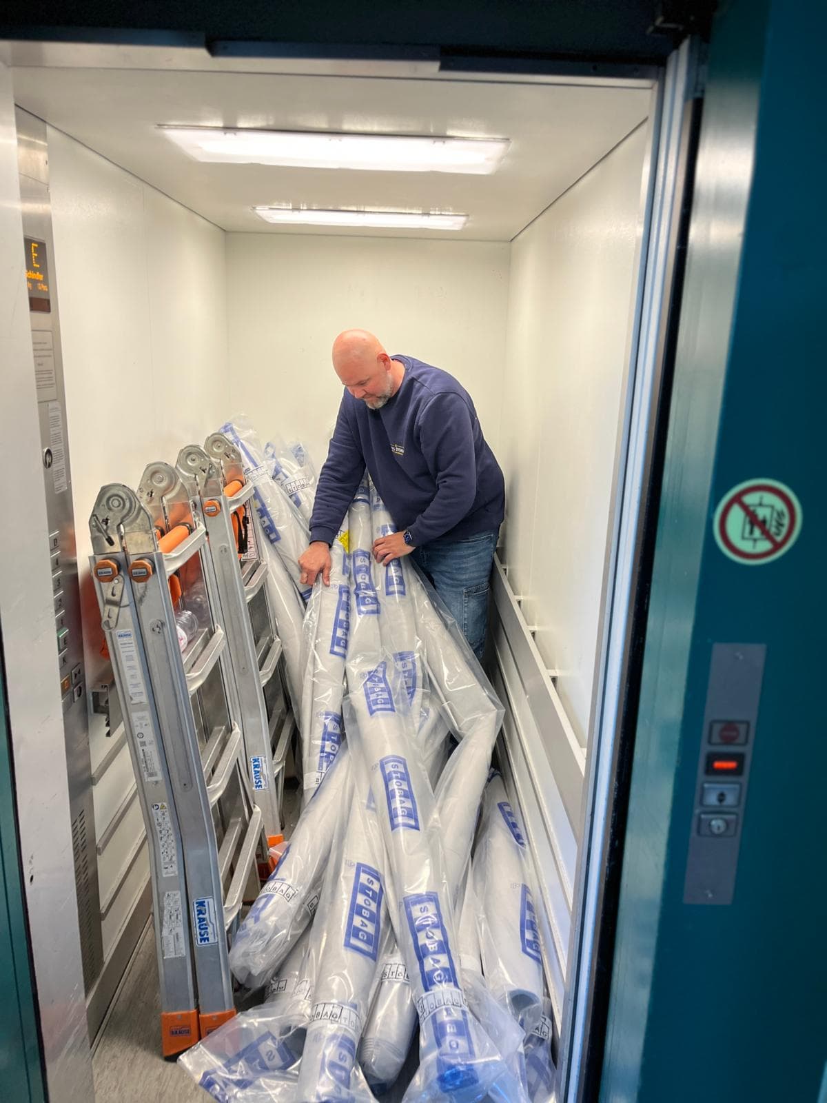 König Storen Mitarbeiter mit Material und Leitern im Warenlift